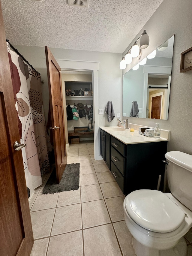 bathroom featuring vanity, toilet, tile patterned flooring, and a textured ceiling