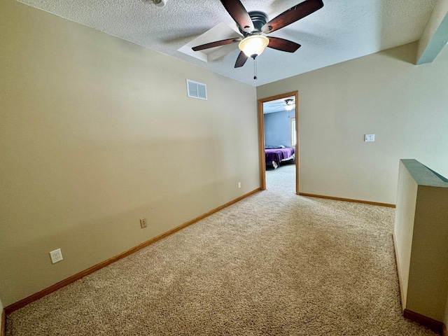 carpeted spare room with ceiling fan and a textured ceiling