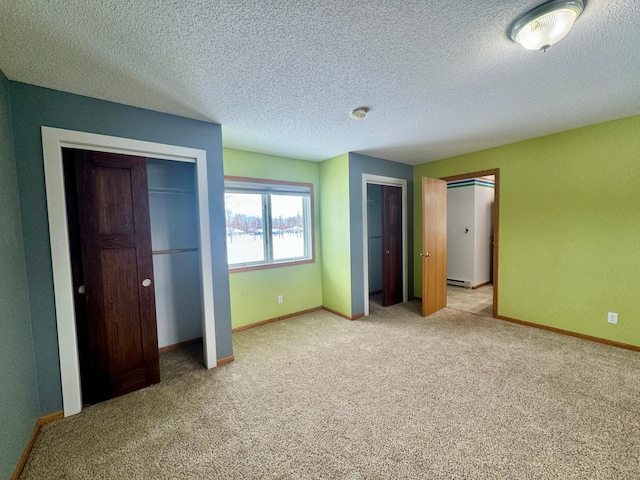 unfurnished bedroom with multiple closets, a baseboard radiator, carpet floors, and a textured ceiling