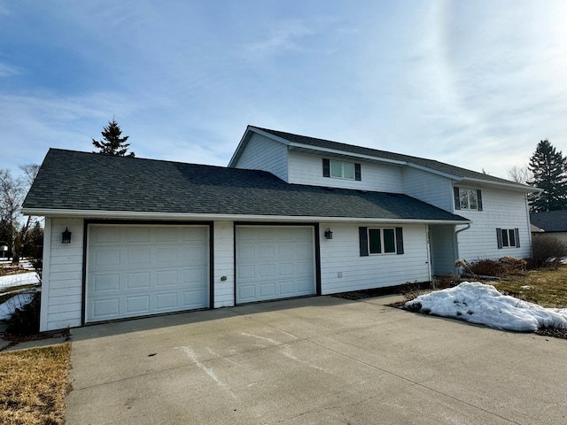 traditional-style home featuring an attached garage, roof with shingles, and driveway