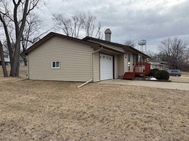 view of side of property featuring a garage and a lawn