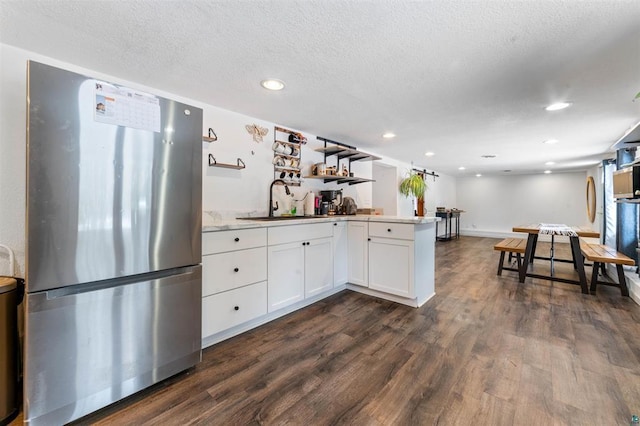 kitchen with sink, stainless steel refrigerator, white cabinetry, a textured ceiling, and dark hardwood / wood-style flooring