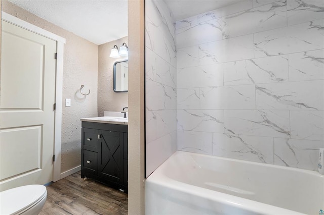 full bathroom featuring hardwood / wood-style flooring, vanity, tiled shower / bath, and toilet