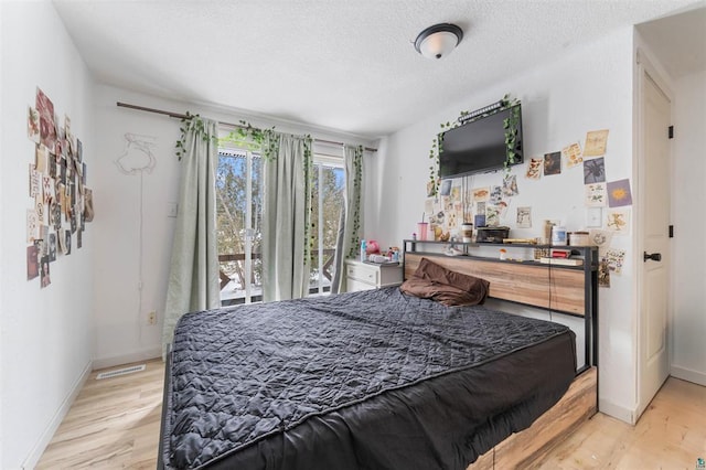 bedroom with access to outside, a textured ceiling, and light wood-type flooring