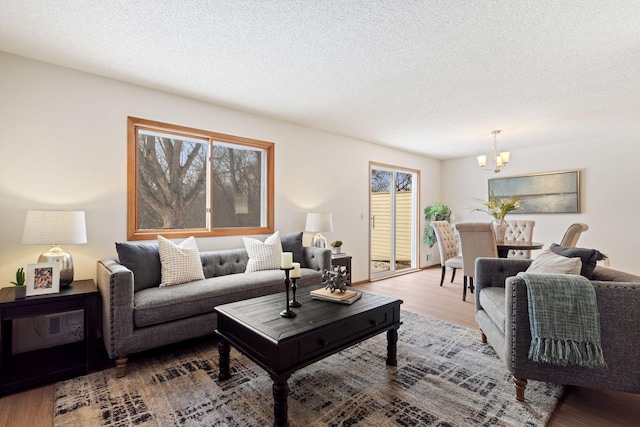 living room with hardwood / wood-style floors, a notable chandelier, and a textured ceiling