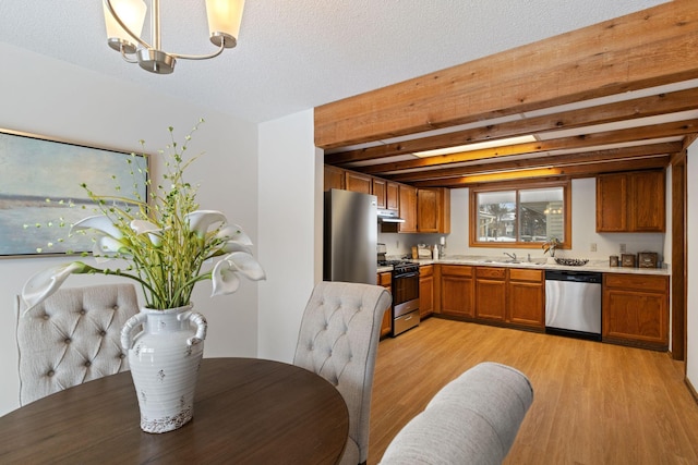 kitchen featuring beam ceiling, light hardwood / wood-style floors, a textured ceiling, and appliances with stainless steel finishes