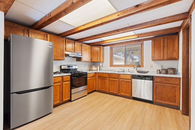 kitchen with sink, stainless steel appliances, beamed ceiling, and light wood-type flooring