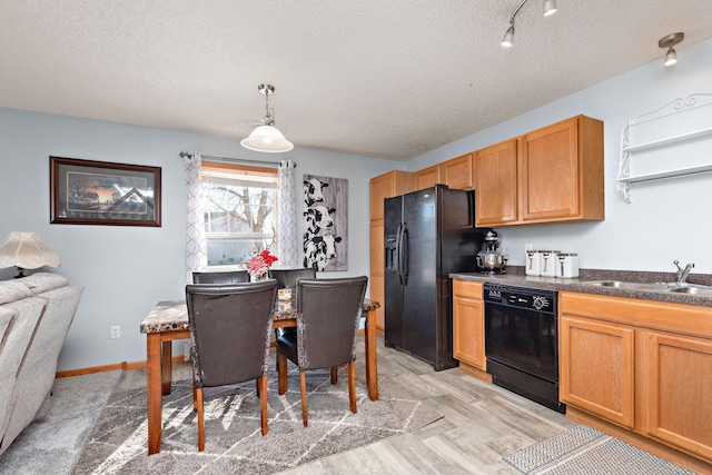 kitchen with sink, a textured ceiling, light hardwood / wood-style flooring, hanging light fixtures, and black appliances