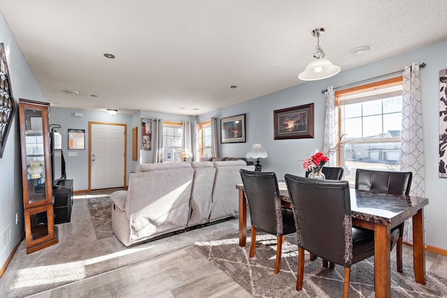 dining space with wood-type flooring and a textured ceiling