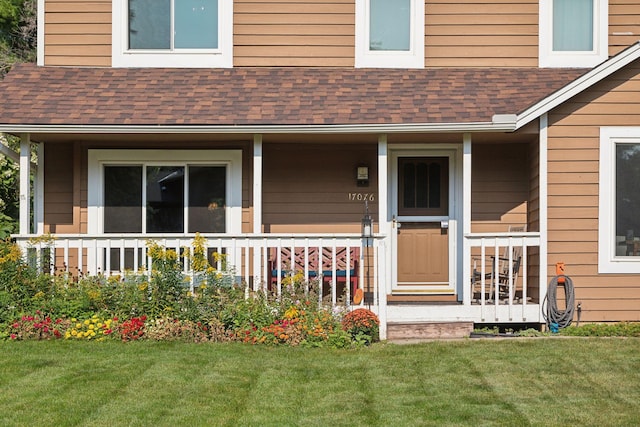 view of exterior entry featuring a porch and a yard