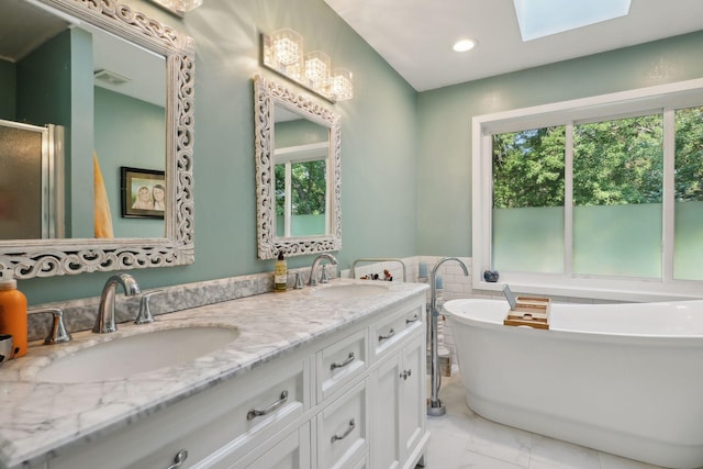 bathroom featuring vanity, a tub to relax in, a healthy amount of sunlight, and a skylight