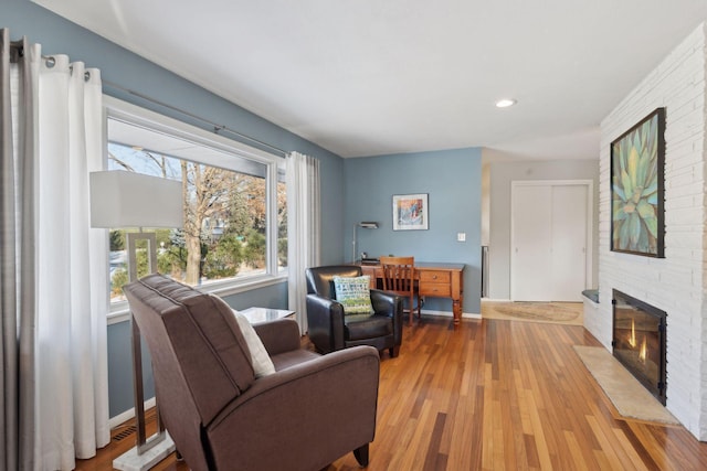 living room featuring a brick fireplace and light hardwood / wood-style flooring