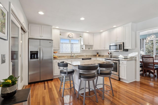 kitchen featuring white cabinetry, sink, a kitchen breakfast bar, stainless steel appliances, and light stone countertops