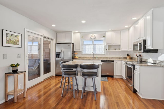 kitchen with a kitchen island, a breakfast bar, white cabinetry, sink, and stainless steel appliances