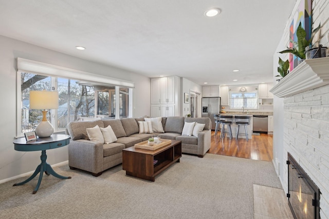 living room with light wood-type flooring, sink, and a fireplace