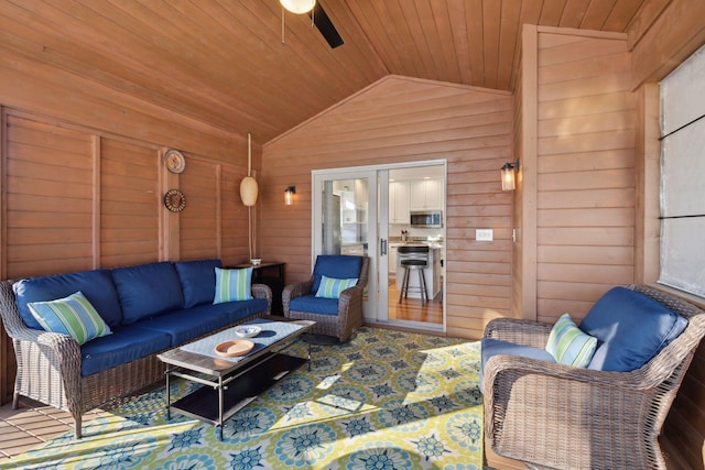 living room with lofted ceiling, wooden ceiling, ceiling fan, and wood walls