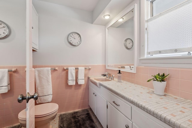 bathroom featuring vanity, toilet, and tile walls