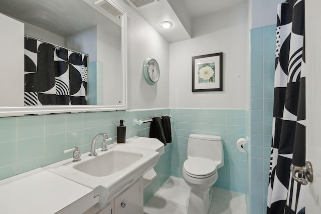 bathroom with tile patterned floors, vanity, toilet, and tile walls