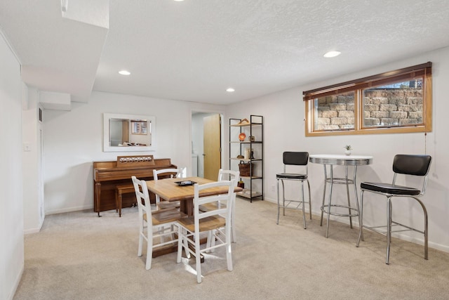 dining space with light carpet and a textured ceiling