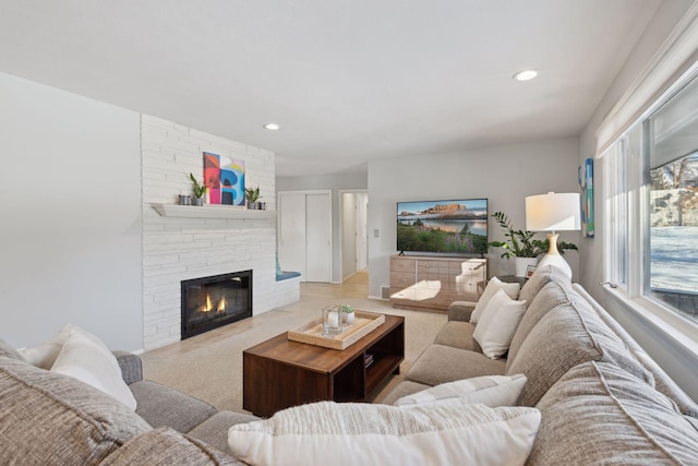 carpeted living area featuring a stone fireplace and recessed lighting