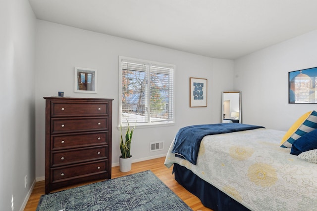 bedroom with visible vents, light wood-style flooring, and baseboards