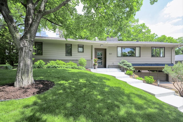 view of front of house featuring brick siding, an attached garage, a chimney, and a front yard