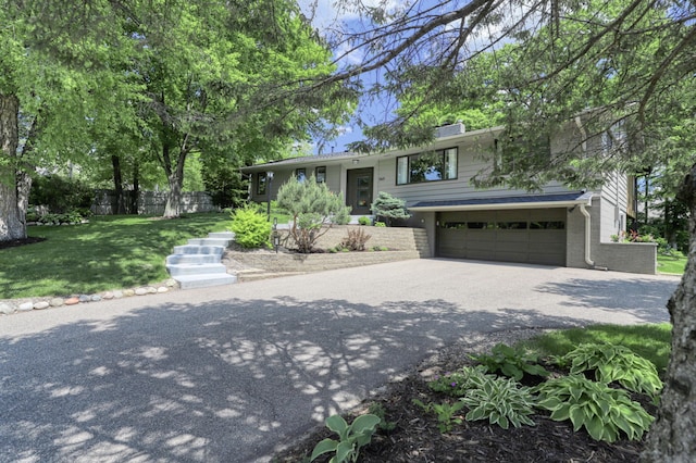 view of front of home with driveway, fence, a front yard, an attached garage, and brick siding