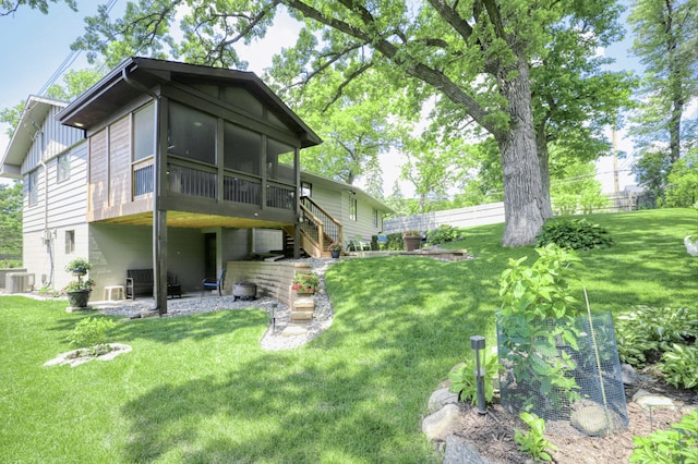 rear view of house featuring stairway, cooling unit, fence, a yard, and a sunroom