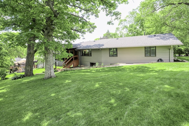 back of house featuring a lawn, a chimney, and a shingled roof