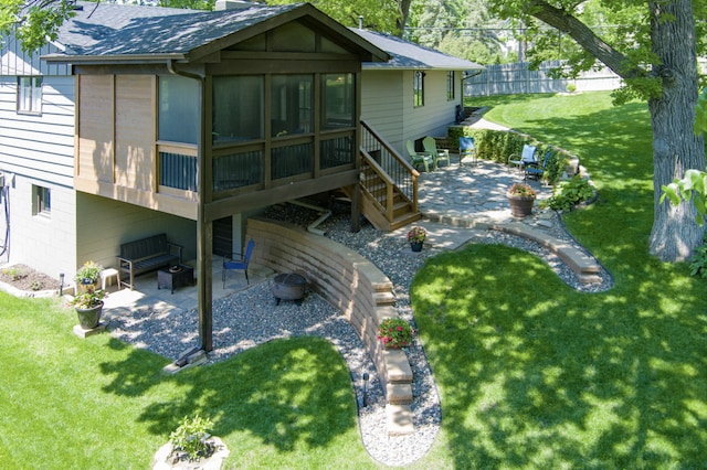 back of property featuring a patio, a yard, a sunroom, a shingled roof, and a chimney