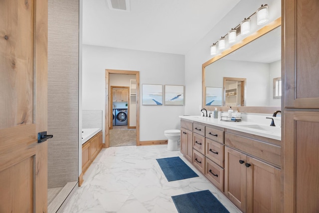 bathroom with vanity, washer / dryer, a washtub, and toilet