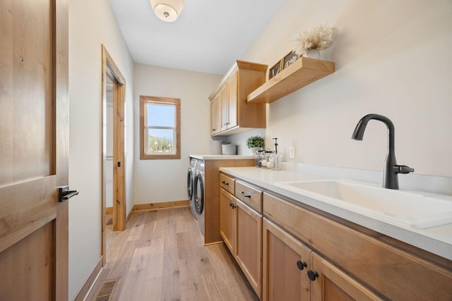 washroom with cabinets, sink, washer and clothes dryer, and light wood-type flooring