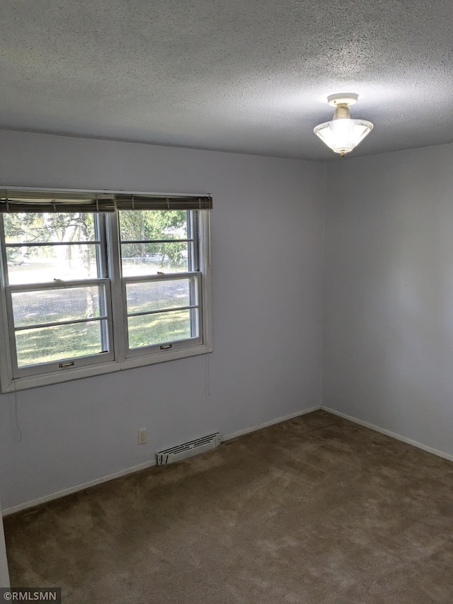 empty room featuring a baseboard radiator, carpet, and a textured ceiling