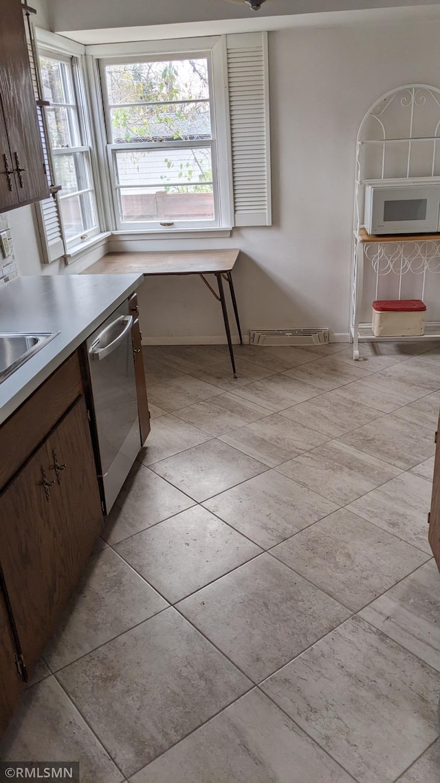 kitchen featuring sink, dark brown cabinets, stainless steel dishwasher, and light tile patterned flooring