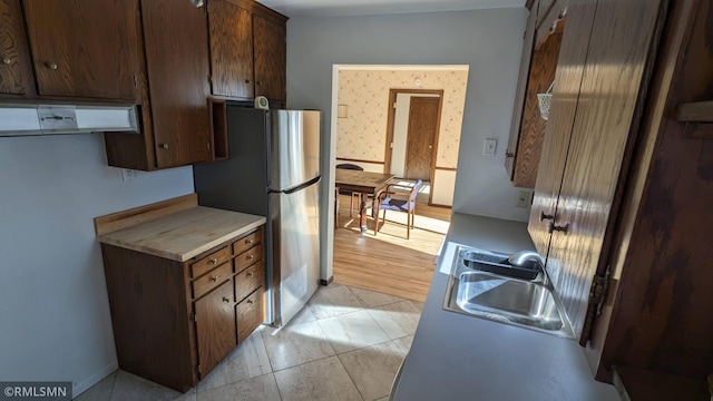 3501 Virginia Ave S, Saint Louis Park, MN 55426 - kitchen with a sink, under cabinet range hood, freestanding refrigerator, light countertops, and dark brown cabinets