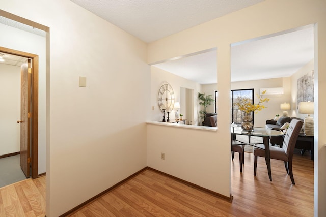 hall with an AC wall unit and light hardwood / wood-style floors