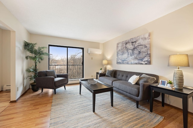 living room with a wall mounted air conditioner, light hardwood / wood-style floors, and baseboard heating