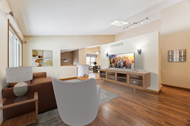 living room with lofted ceiling, dark wood-style floors, visible vents, and a textured ceiling