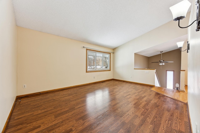 unfurnished living room with lofted ceiling, dark wood finished floors, a textured ceiling, and baseboards