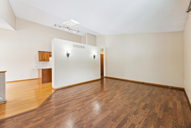 spare room with lofted ceiling, baseboards, visible vents, and dark wood-style flooring