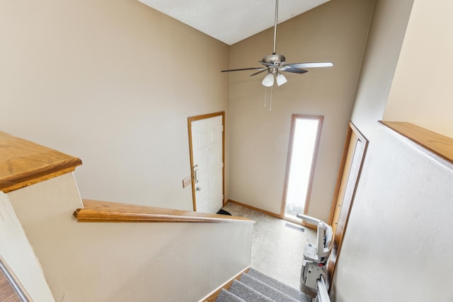 staircase featuring a healthy amount of sunlight, carpet, high vaulted ceiling, and ceiling fan