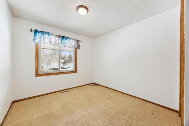 carpeted spare room with a textured ceiling, visible vents, and baseboards