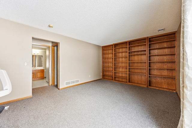 unfurnished bedroom with a textured ceiling, carpet floors, visible vents, and baseboards