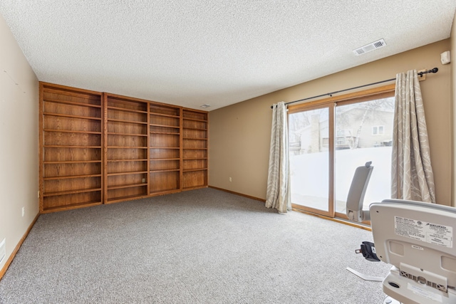 empty room featuring carpet, baseboards, visible vents, and a textured ceiling