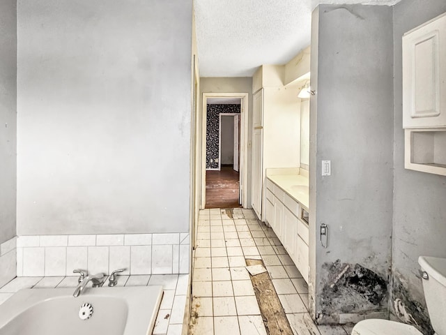 bathroom with tile patterned floors, toilet, a textured ceiling, vanity, and a tub