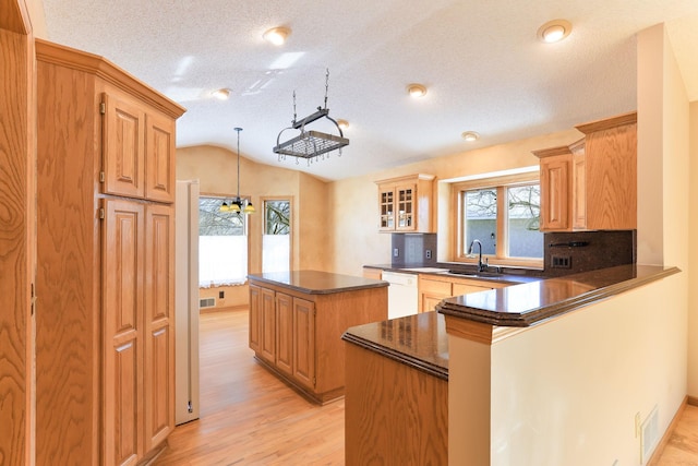 kitchen featuring hanging light fixtures, lofted ceiling, a kitchen island, white dishwasher, and kitchen peninsula