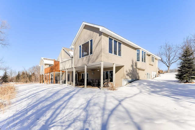 snow covered rear of property featuring ceiling fan