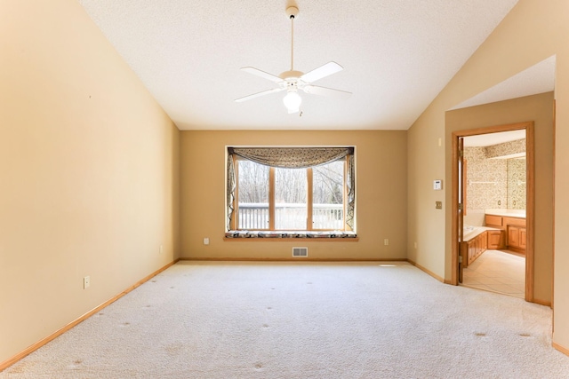 carpeted spare room featuring lofted ceiling, ceiling fan, and a textured ceiling