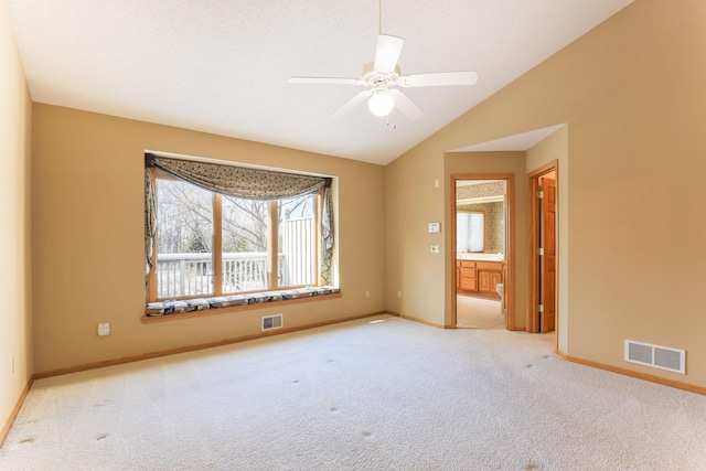 empty room with light carpet, vaulted ceiling, ceiling fan, and a textured ceiling