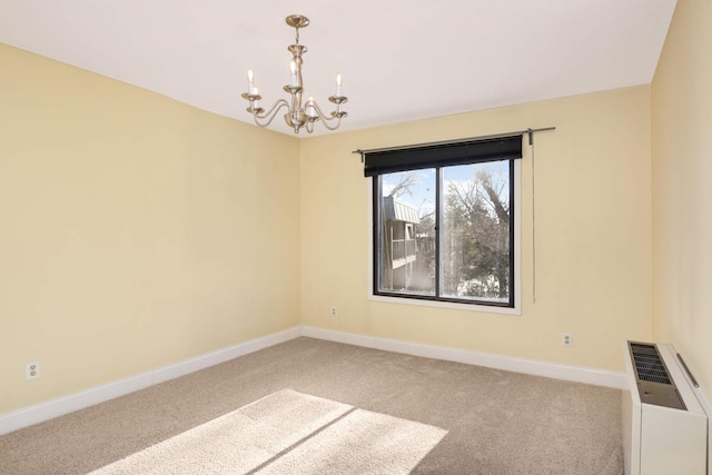 carpeted empty room featuring a chandelier